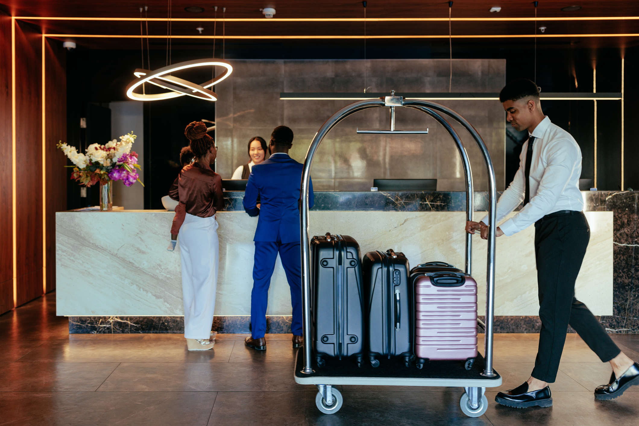 Reception desk with guests and luggage cart